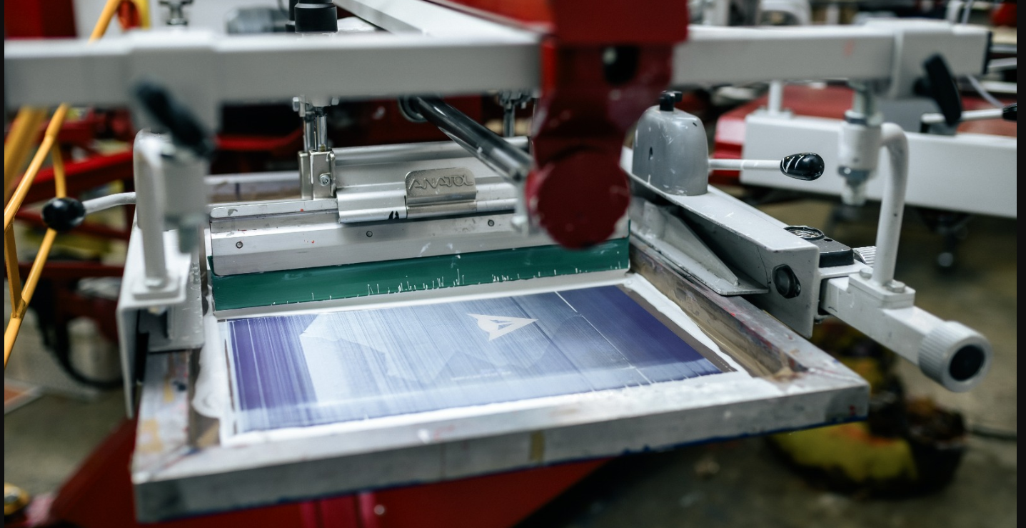 Anatol screen printing machine with a green squeegee applying blue ink on a fabric for precise pressure setup